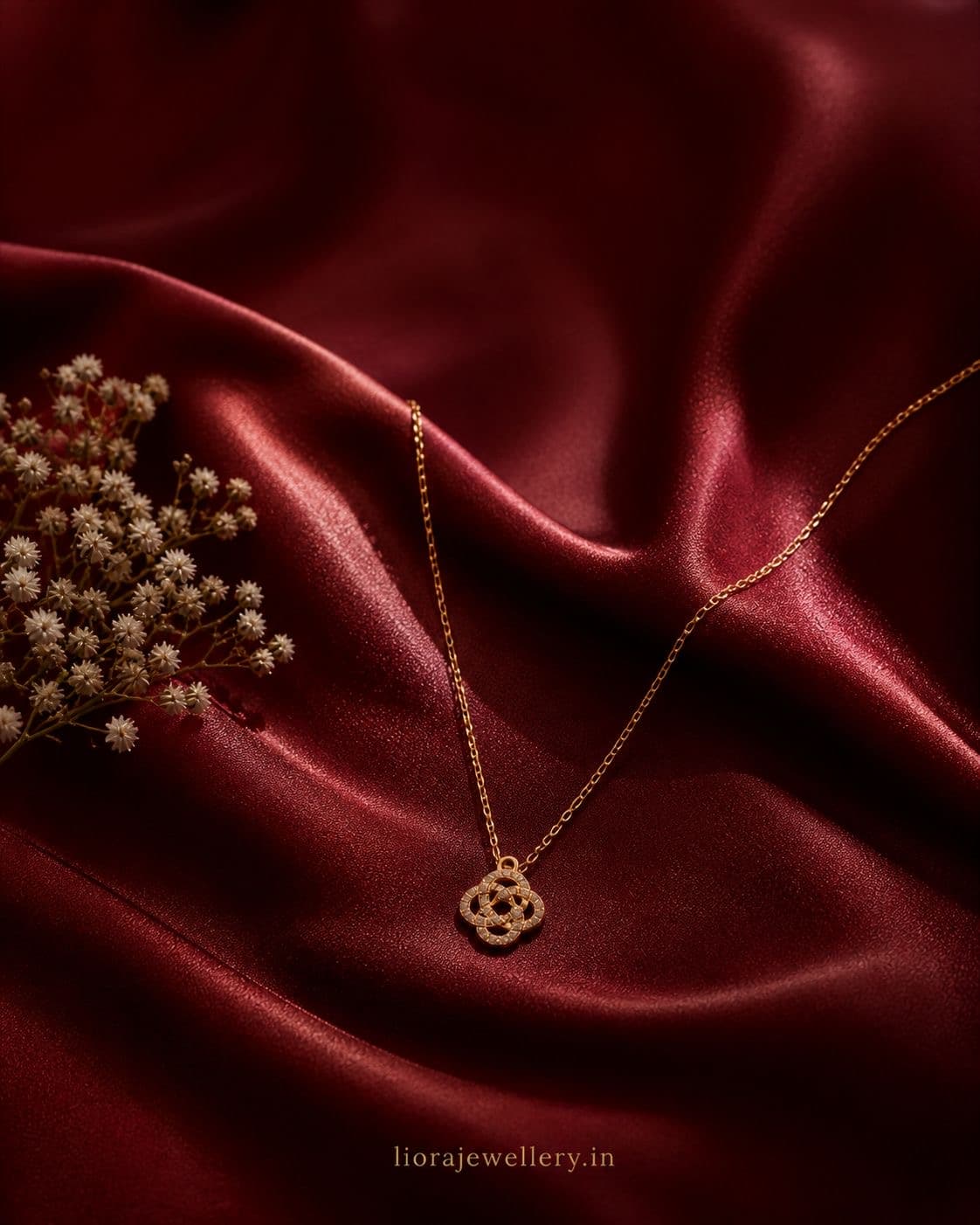 Editorial backdrop — ZYRO knot pendant on burgundy silk